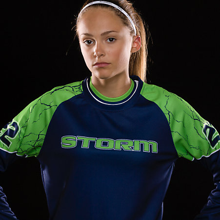 A girl in a green and blue softball jersey
