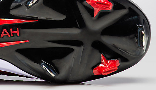 The red and black sole of baseball shoe with metal cleats
