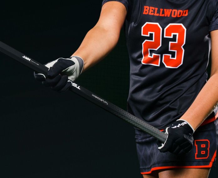 Female lacrosse player holding stick with black and white gloves