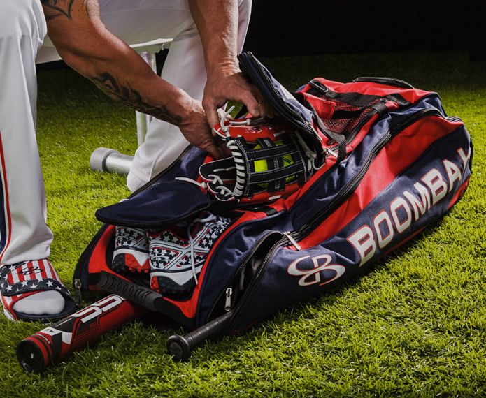 Red and navy Beast bag with baseball equipment being put inside